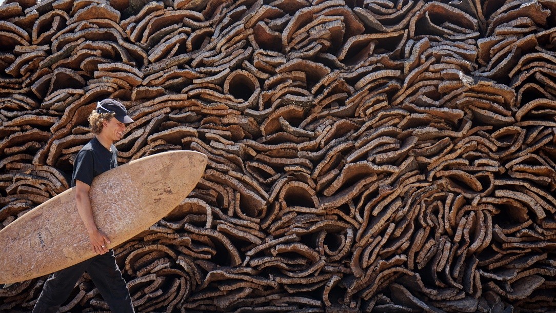 A surfer with a Hara board in front of stacked cork bark